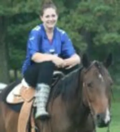 Rochina Ahrens' staff photo from Shinnecock Animal Hospital where she is outside saddled up on a brown horse.